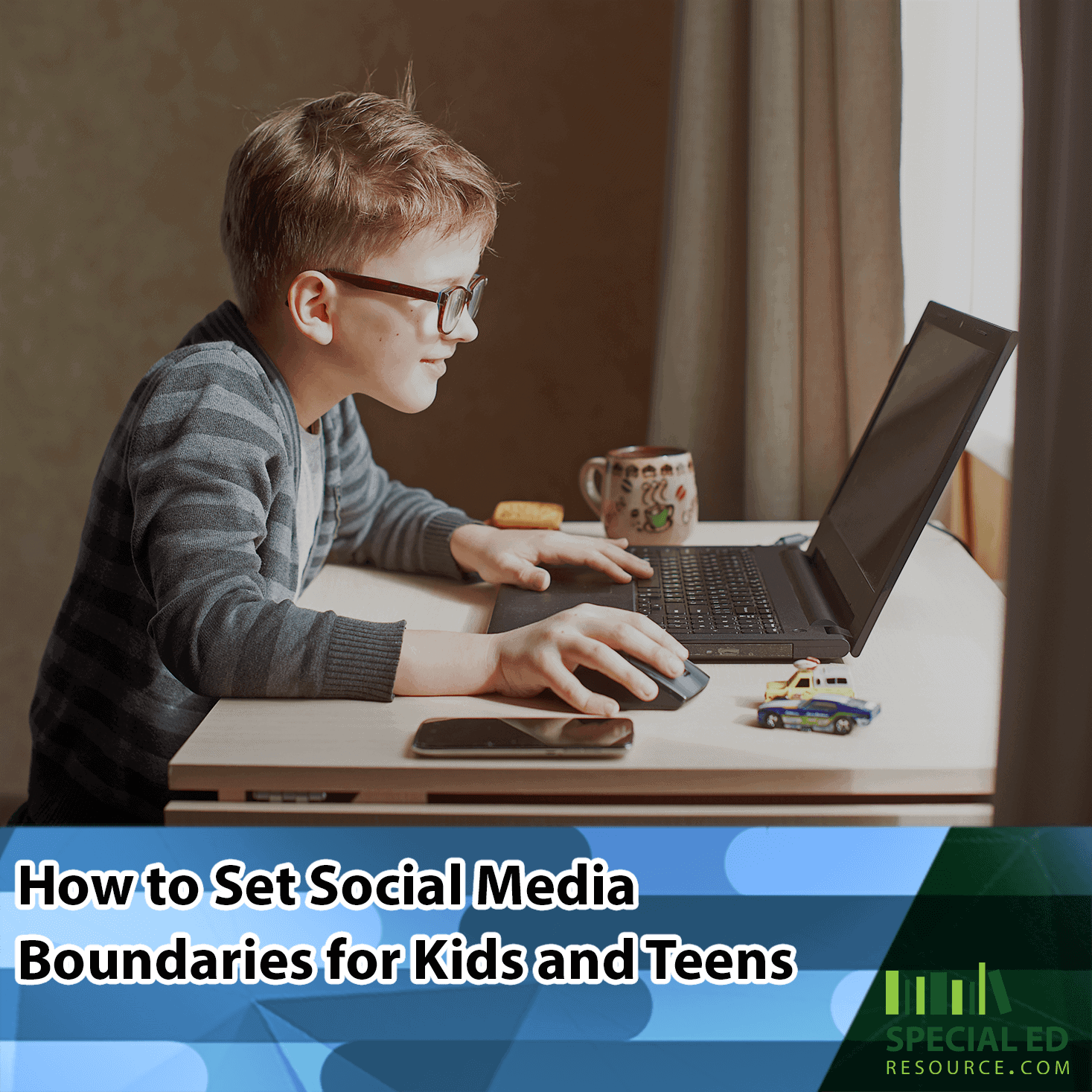 A young boy with glasses focused on using a laptop at a desk, with a mug and smartphone nearby, using the social media boundaries for kids his parents established from the tips in this blog post by https://stagingsite.specialedresource.com/